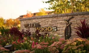 A close up of the blooming flowers in front of the stonework sign of the Trillium Woods entrance
