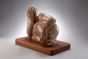 Bronze sculpture of a man laying on his side 