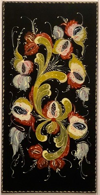 A green, red, and black painting done in the rosemaling style.
