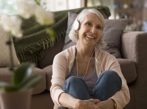 A senior woman listens to music through headphones as part of Music and Memory.