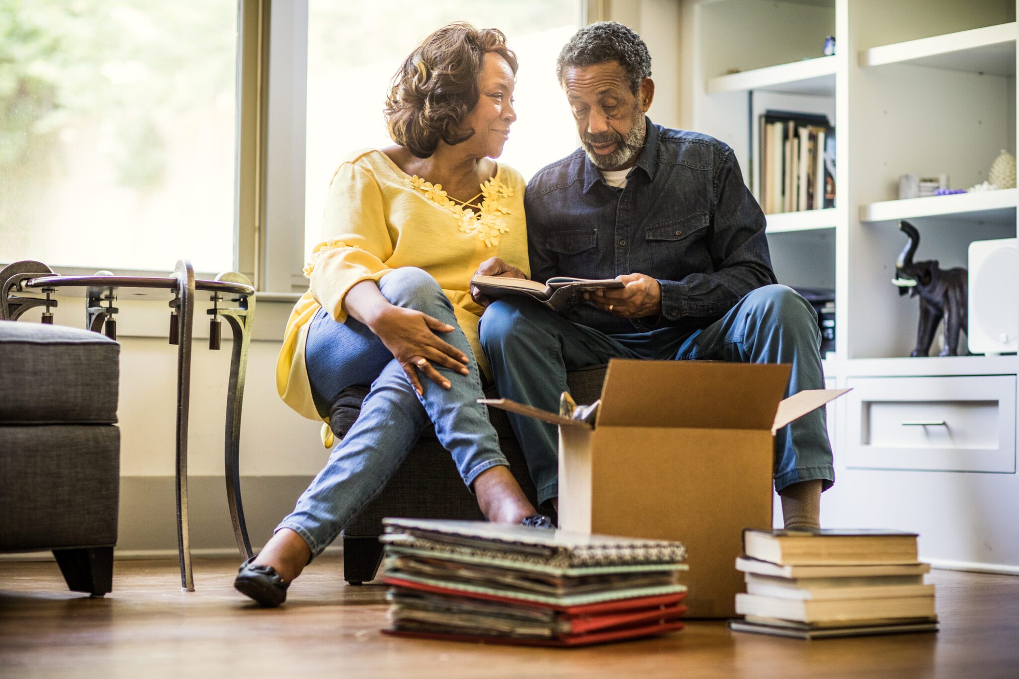 An older couple sit together and look through books before packing them away