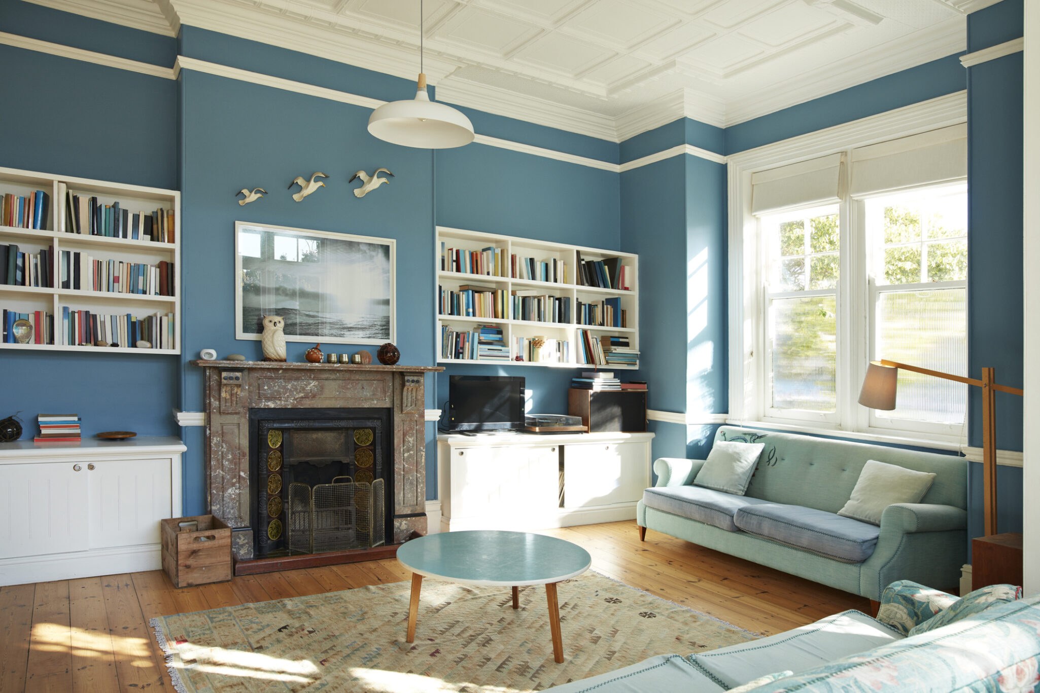 Blue walls with white trim living room with fireplace and white bookshelves