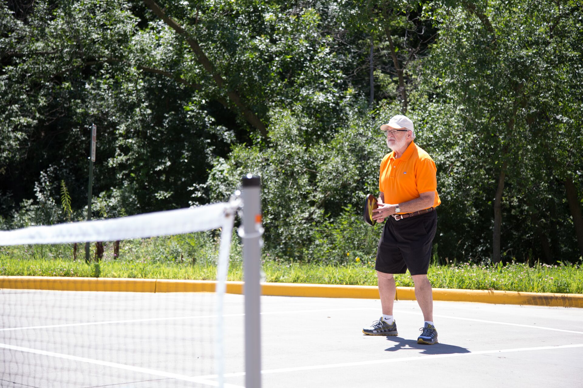 A senior man playing pickleball on a sunny day.