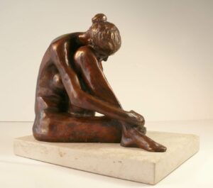 Bronze sculpture of a woman sitting with her knee drawn up